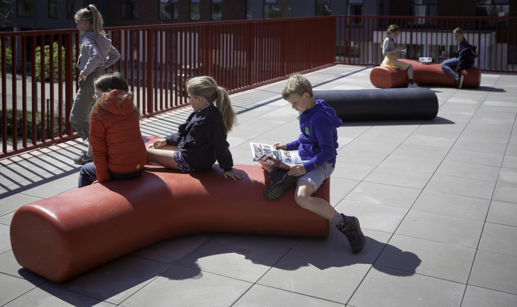 Boys and girls studying onto Durbanis benches. The outdoor design firm that manufactures its furniture in recycled plastic.