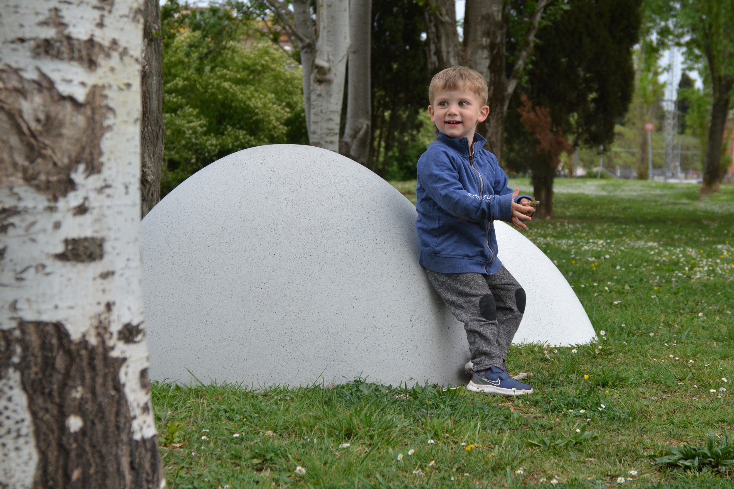 Child resting on an urban element in the shape of a small mountain