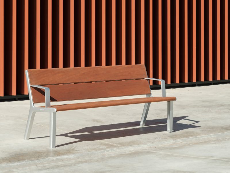 Linear bench with armrests and backrest, with four wooden slats and rounded edges for greater comfort and ergonomics