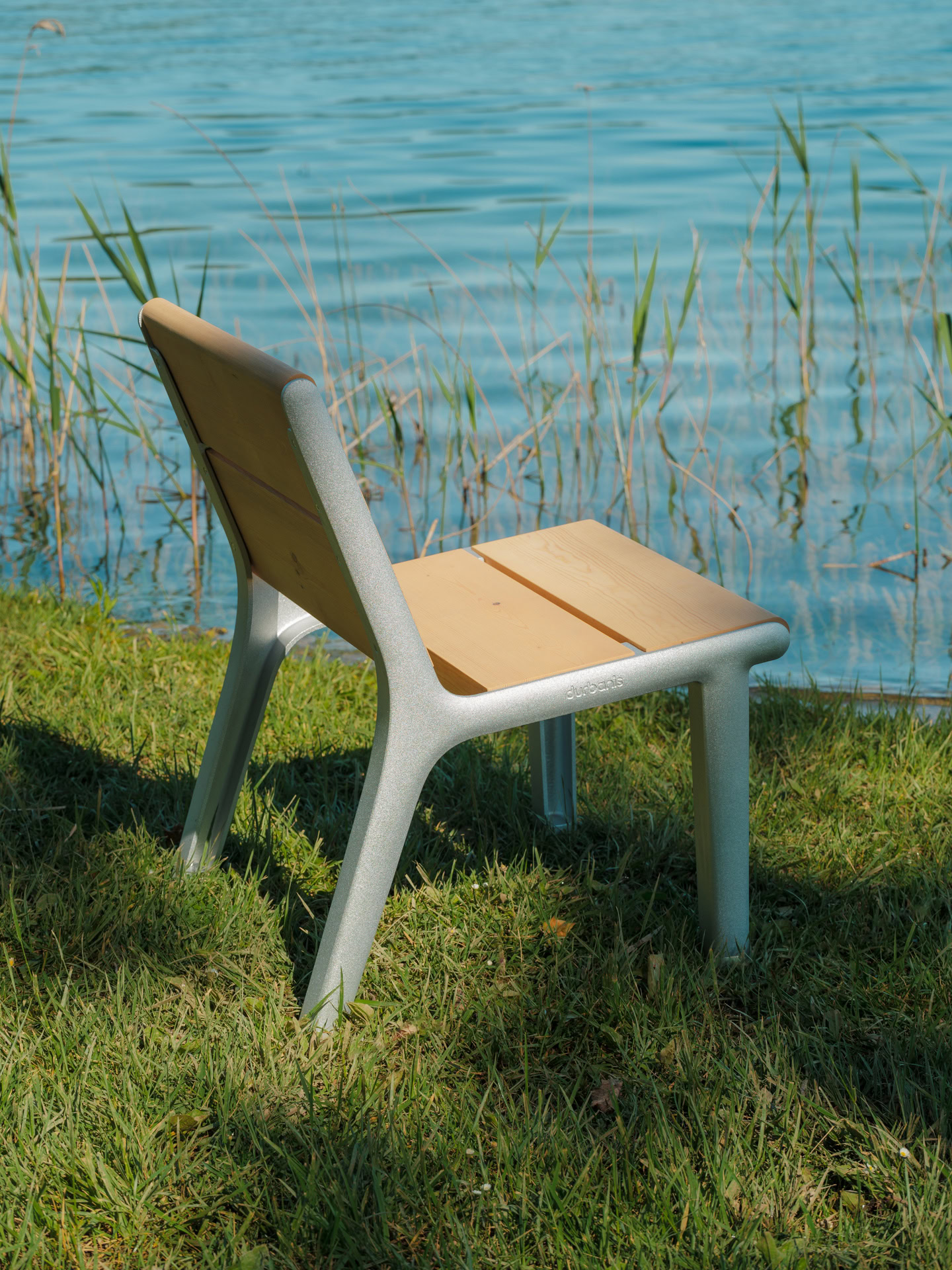 Individual wooden and aluminum bench in a park with a lake